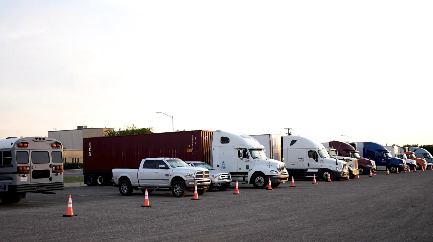 Semi trucks and a container on chassis parked in a row at Longhorn Truck Parking